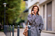 Attractive mid adult woman walking on the city street and using her smartphone