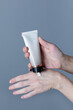 Woman hands holding hand cream on grey background