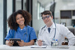 © SOMKID - female African American doctor and doctor man working with clipboard in hospital.