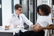 © SOMKID - Male doctor examining a pregnant African American woman at the hospital.