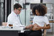 © SOMKID - Male doctor examining a pregnant African American woman at the hospital.