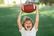 © Volodymyr - American boy playing a american football or rugby in park. Sporty kids. Football player holding game ball.