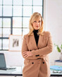 Blond haired businesswoman wearing blazer and standing at the office