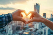 © Degimages - Cropped shot of an unrecognizable couple making a heart shape with their hands against a city background.