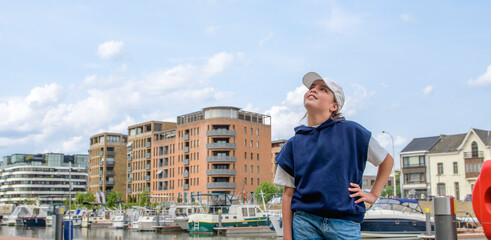 Wall Mural - A young girl stands on a pier looking out at the sky. Banner size