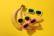 Bananas and sunglasses on yellow background, top view