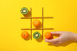 Kiwi, tangerines, straws and hand on yellow background, top view