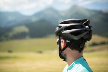 Wall Mural - Rear view of cyclist in helmet admire mountains and beautiful nature, standing by bicycle. Concept of healthy lifestyle.