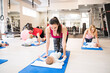 © Halfpoint - Mother smiling at baby while performing exercise above. Group exercise class, fitness or pilates for parents. Moms staying active while boding with babies.