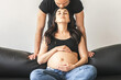 Pregnant woman sitting on couch, man standing over her