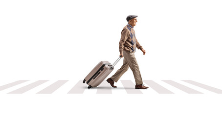 Wall Mural - Full length profile shot of an elderly man pulling a suitcase and walking on a street