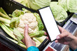 Cauliflower vegetable in hand and smartphone isolated white