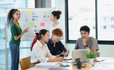 Asian group of people working with documents have financial or marketing charts on a board room table at a business presentation or seminar.