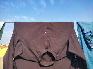 In the courtyard of the house, washed wet clothes are hung on a wire to dry in the sun. Clothes hanging on a wire in a sun. Photo taken in day sunlight against blue sky background