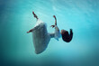 © master1305 - Captivating beauty surrounded by gentle waves of blue ocean. Tender girl falling down the ocean, levitating underwater. Concept of surrealism, beauty, mystery and fantasy, freedom