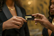 a upclose businesswoman handing a another woman, a black card with a gold 