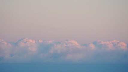 Wall Mural - Fluffy clouds sunset sky above calm sea with space for text. Miminal coastal banner.