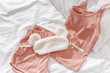 Top view pink pajama and fluffy eye sleep mask on white crumpled bedclothes, cushion and blanket. Cozy pyjamas for comfort rest at night. Flat lay from singlet, shorts, sleeping mask pink color
