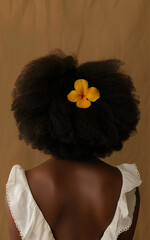 a black woman with a large afro hairstyle, a yellow flower in her long hair, wearing a white dress, taken from behind, against a beige background with back lighting