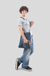 young man smiling and handsome dressed in jeans and t-shirt with shoulder bag isolated on gray background