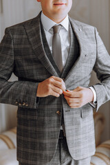 Wall Mural - A man in a suit is getting ready to go out. He is wearing a plaid jacket and a tie
