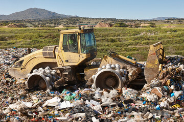 Wall Mural - Heavy machinery shredding garbage in an open air landfill. Pollution