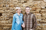 Fototapeta Panele - Happy Middle-Aged Couple Embracing Outdoors Against a Stone Wall