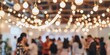 © tashechka - A defocused shot capturing the lively atmosphere of a social event with hanging lights and attendees.