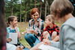 © Halfpoint - Young students analyzing water quality, ph level with indicator strips during biology field teaching class. Female teacher during outdoor active education.