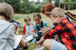 © Halfpoint - Young students analyzing water quality, ph level with indicator strips during biology field teaching class. Female teacher during outdoor active education.