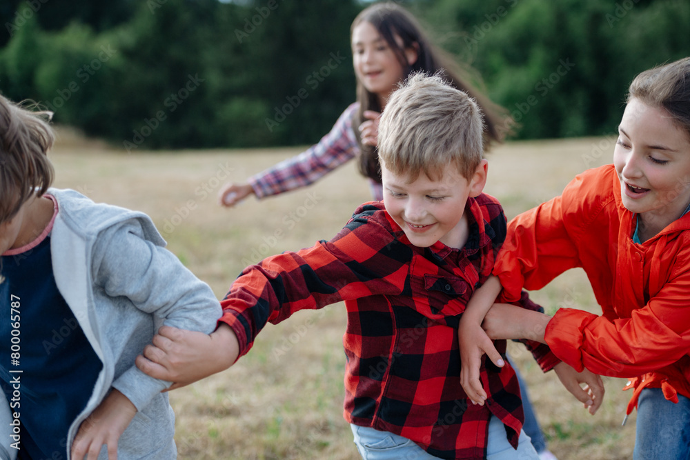 Young students playing with teacher outdoors, in nature, during field ...