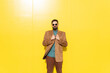 © VISTA by Westend61 - Smiling man wearing brown jacket and sunglasses in front of yellow wall