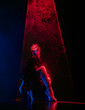 Stylish woman in latex coat under colorful illumination, laser light, neon smoke club. Projection illusion mapping. Futuristic model.