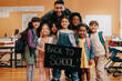 © Jacob Lund - Primary school pupils excited to learn on first day of co-ed class. Teacher and kids hold a back to school sign