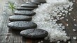Zen-like display of fine sea salts and flat spa stones, creating a path on a textured wooden table