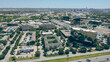 Northwest Dallas business park with ample parking spaces, group of office buildings, hotels, restaurants in Love Field neighborhood with mid-town buildings skylines background, aerial view