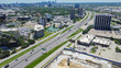Aerial view construction site wooden framing next to Stemmons Freeway Interstate Highway I-35E, business park in Northwest Dallas, group of office buildings, hotels downtown skylines background