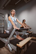 Young women exercising in a gym on pilates machines.