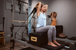 Young women exercising in a gym with personal trainer on pilates machine.