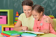 Portrait of little girl with her mother doing homework