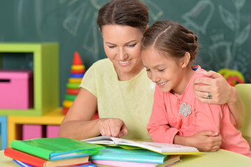 Portrait of little girl with her mother doing homework