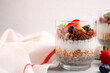 Tasty granola with berries, nuts, yogurt and chia seeds in glass on white table, space for text
