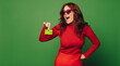 Vibrant fashionable woman smiling ready to swipe her credit card on green background