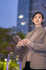 Wall Mural - Confident Businesswoman with Tablet in Urban Evening