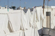 White various clothes hanging and drying in wind on rope. Laundry with clothes pins on line outdoors. Spanish rooftop. Summer Mediterranean still life, city life. No people.
