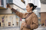 Fototapeta  - Urban Woman Enjoying Coffee and Taking Selfie