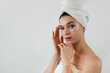 © RomanR - Young girl wearing white towel using cosmetic patches under her eyes isolated on white