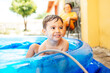 © kleberpicui - Happy child playing in inflatable home pool in summer. Active outdoor recreation.
