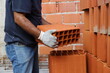 Builder holding a brick. Construction worker lifting a block. Concept of architecture, construction, industry, construction worker. Professional bricklayer working on house construction. 
