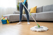 happy Female housekeeper service worker mopping living room floor by mop and cleaner product to clean dust.